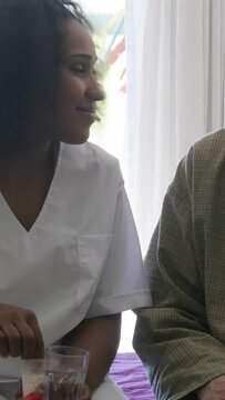 Female doctor helps ederly patient in hospital. Vertical Video