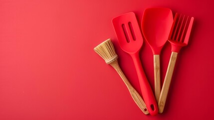 Kitchen utensils set with silicone spatula and basting brush isolated on a solid red background