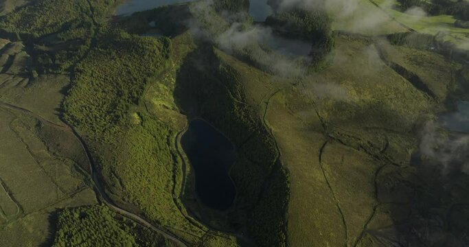 Aerial view of Seven Lakes surrounded by lush forest, hills, and clouds, Capelas, Azores, Portugal.
