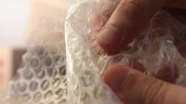 Man's fingers burst bubbles on plastic wrap. Air bubble film close up. Antistress wrap 
