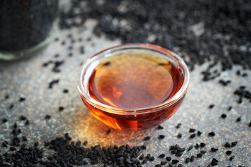 Black cumin or Nigella sativa seed oil in a glass bowl. Healthy anti-inflammatory supplement.