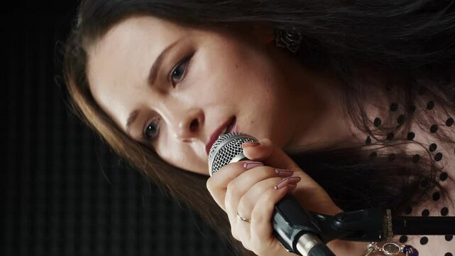 Woman at rehearsal vocal studio singing song into microphone. Vertical video