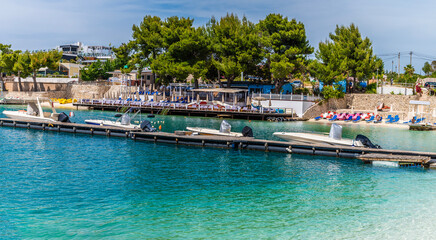 A view past boats moored on a jetty from the beach at Ksamil, Albania in summertime