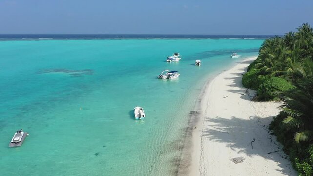 Aerial view of idyllic beach with boats and ripple in Thoddoo Atoll, Maldives.