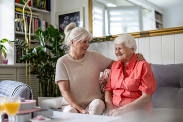 Happy senior woman with her adult daughter at home
