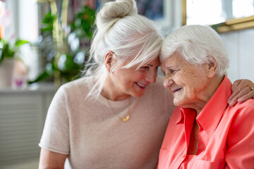 Happy senior woman with her adult daughter at home
