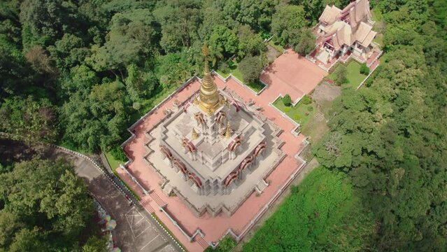 Aerial view of temple surrounded by forest and trees, Phrathat Chedi Srinagarindra Stit Maha Santi Khiri, Mae Salong Nok, Chiang Rai District, Thailand.