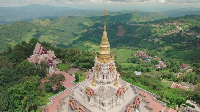 Aerial view of Phrathat Chedi Srinagarindra Stit Maha Santi Khiri temple surrounded by forest and mountains, Mae Salong Nok, Thailand.