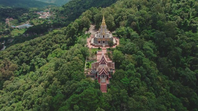 Aerial view of Phrathat Chedi Srinagarindra Stit Maha Santi Khiri temple surrounded by lush forest and mountain, Mae Salong Nok, Chiang Rai District, Thailand.