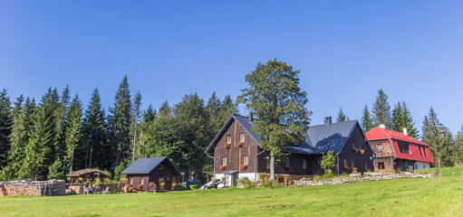 Panorama of a traditional wooden house in the landscape of the Sumava mountains national park, Czechia