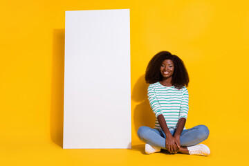 Full length portrait of pretty positive person sitting floor near empty space telephone ui menu isolated on yellow color background