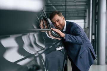 Embracing new automobile. A businessman is in a car dealership
