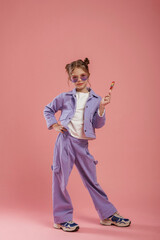 Colorful sweet candy in hand. Cute little girl is against pink background