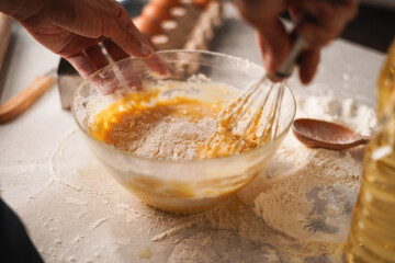 Baking preparation with flour and eggs being whisked in bowl by hand