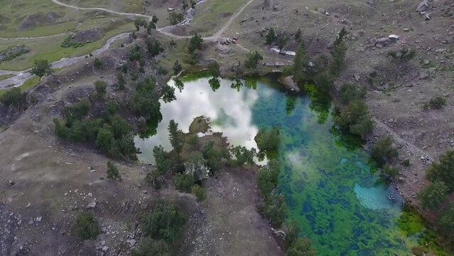 Aerial view of tranquil lake, winding road, and majestic mountains in Naltar Valley, Gilgit, Pakistan.