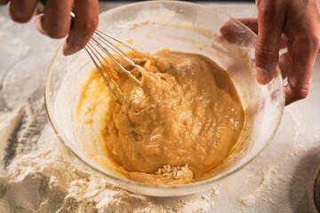 Pastry chef making dough with a whisk. cooking waffle on rustic wooden table with ingredients. Handmade dessert and cooking process