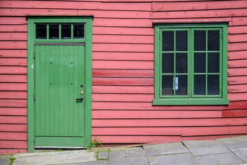 A Green Door and Window on an Old Red Wooden Building in Norway