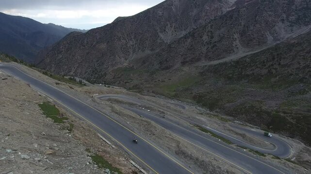 Aerial view of winding road through Babusar Pass with majestic mountain range, Kaghan Valley, Pakistan.