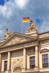 The national flag of Germany is on the roof of a building against the blue sky.