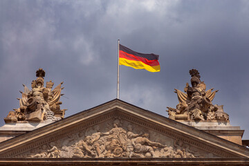 The national flag of Germany is on the roof of a building against the blue sky.