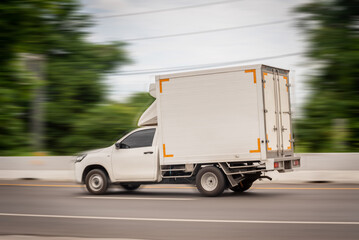 Motion blurred image, of a small white truck for logistics on the roads.