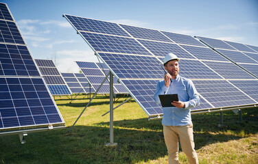 Talking by radio. Engineer with photovoltaic solar panels outdoors at daytime