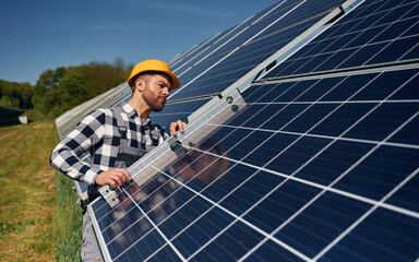 Using the leveler tool. Engineer with photovoltaic solar panels outdoors at daytime