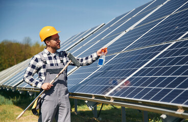 Procedure of cleaning the surface. Engineer with photovoltaic solar panels outdoors at daytime