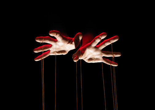 Puppeteer's hands with strings on each finger on black background.