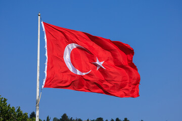 Turkish flag, on a red background white star and moon. Turkish flag flies in the wind against the backdrop of Istanbul