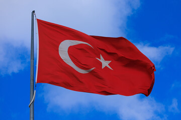 Turkish flag, on a red background white star and moon. Turkish flag flies in the wind against the backdrop of Istanbul