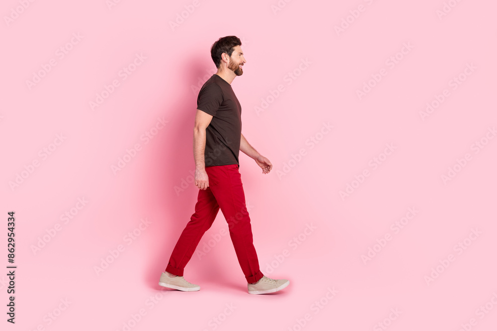 Wall mural full length photo of good mood man with bristle dressed brown t-shirt red pants walk empty space iso