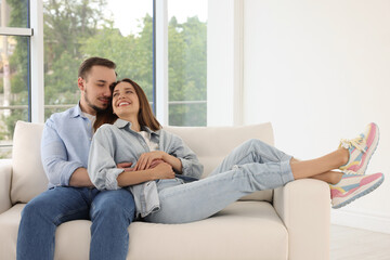 Obraz premium Man hugging his happy girlfriend on sofa at home