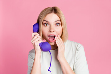 Naklejka premium Portrait of ecstatic impressed girl with bob hair wear t-shirt discuss rumors on retro cable phone isolated on pink color background