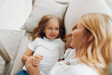 Obraz na płótnie Canvas Mother and daughter bonding on the couch while engaging in a heartwarming hand comparison activity