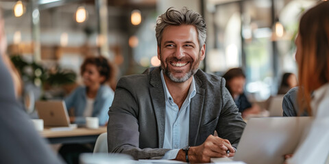 Smiling business people having a discussion in an office crowded around a laptop 