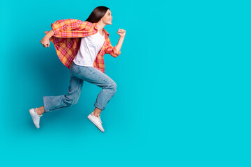 Full body profile portrait of nice girl jump run empty space ad wear checkered shirt isolated on turquoise color background © deagreez