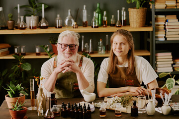 Senior perfumer sitting at his workplace with huge number of perfume samples and essential oils,...