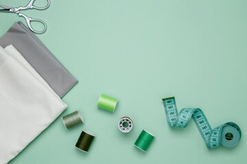 Composition with various threads and sewing accessories on green background. Top view, copy space