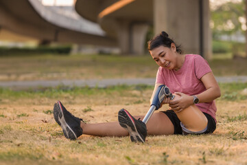 Athlete with prosthetic leg doing warm up exercise on park. Woman wearing prosthetic equipment for...