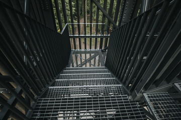A close-up view of a metal staircase inside an industrial structure, with light filtering through...