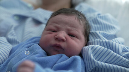Newborn baby close-up in serene contemplation after childbirth, first day of infant's life resting...