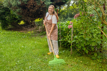 Raking leaves. Picture of happy woman working with tools in the garden, preparing the garden for winter, spring. Taking care of the garden. High quality photo