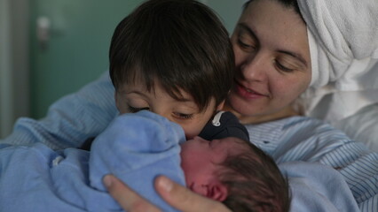 Newborn Introduction to Sibling at Hospital - Young Brother Cradles New Baby as Mother Observes,...