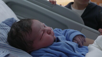 Newborn baby infant being watched by brother at hospital clinic after childbirth, family moment...