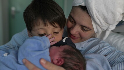 Newborn Introduction to Sibling at Hospital - Young Brother Cradles New Baby as Mother Observes, Celebrating First Family Bonding Moment