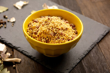 Manioc and soy farofa flour in a yellow ceramic bowl in stone board