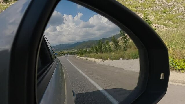 Automobile in motion. View in the rear view side mirror of a auto, driving a car along the track