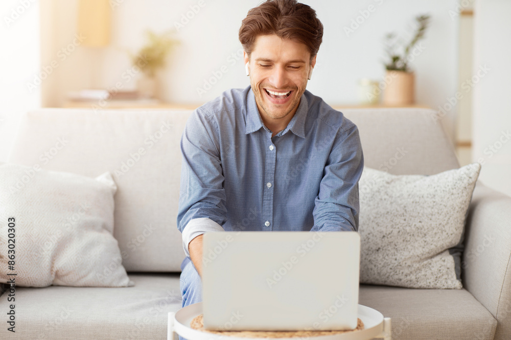 Poster Remote Work Concept. Man Making Video Call Using Laptop Sitting On Couch At Home. Empty Space