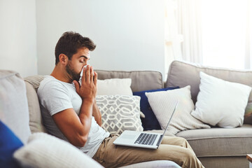 Remote work, laptop and sick man on sofa with tissue for blowing nose, allergies or influenza in...